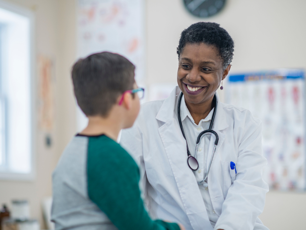 female african american clinician smiling and listening to a young male child